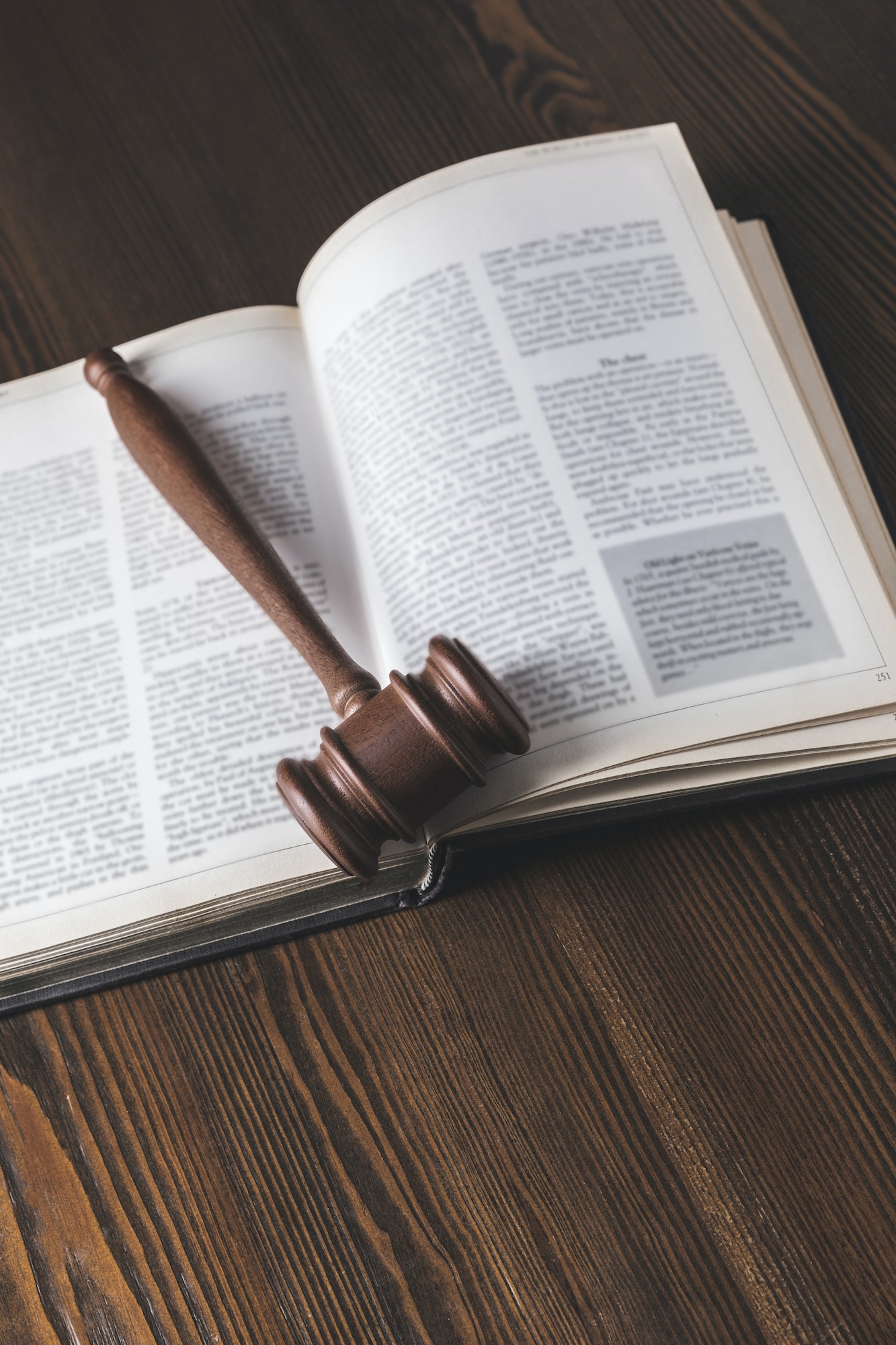 opened juridical book with hammer on wooden table, law concept