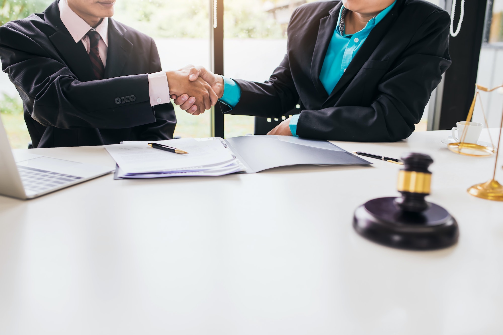 Businessman shaking hands to seal a deal with his partner lawyers or attorneys discussing
